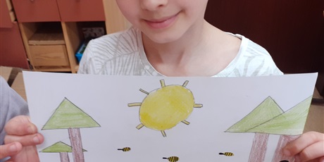Powiększ grafikę: Chłopiec trzyma rysunek przedstawiający drzewa i słońce.
