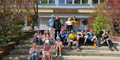 Powiększ grafikę: Uczniowie siedzą na schodach przed wejściem do Domu Kultury.