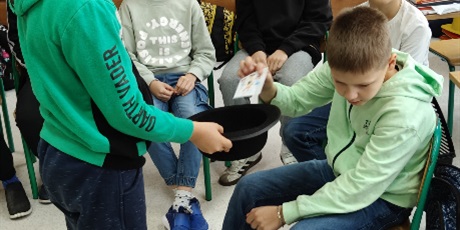 Powiększ grafikę: Dzieciz 3c losują z kapelusza wróżby rysunkowe. 