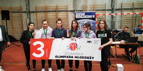 Powiększ grafikę: Sześć dziewcząt z medalami na szyi i pucharem, trzymają planszę z napisem Gdańska Olimpiada Młodzieży-3 miejsce.