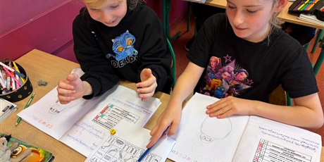 Powiększ grafikę: Uczennice w ławce rysują robota wg kodu.
