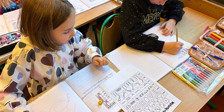 Powiększ grafikę: Uczennice w ławce rysują robota wg kodu.