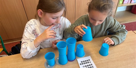 Powiększ grafikę: Dzieci ustawiają wieże z kubków.