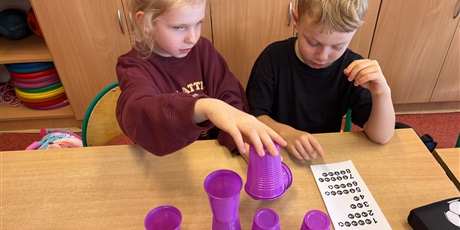 Powiększ grafikę: Dzieci ustawiają wieże z kubków.