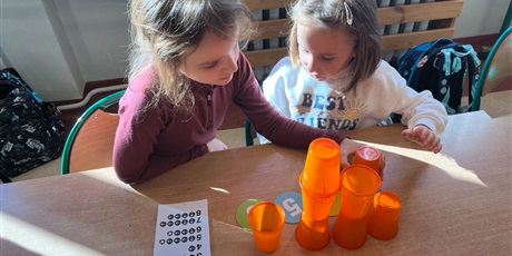 Powiększ grafikę: Dzieci ustawiają wieże z kubków.