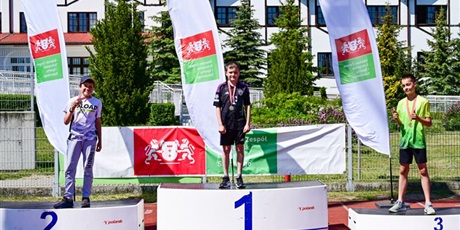 Powiększ grafikę: 3 chłopców stoi z medalami na podium czwartki