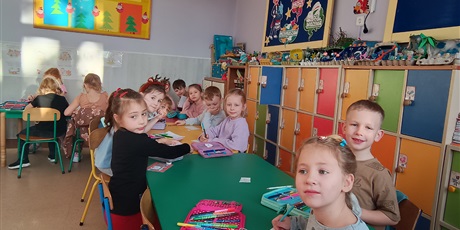 Powiększ grafikę: Dzieci  przy stolikach  ozdabiają kartki świąteczne. 