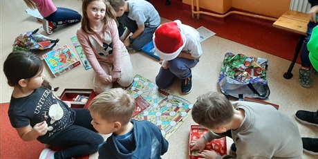 Powiększ grafikę: Dziewczynki I chłopcy siedzą na podłodze, grają w gry planszowe.