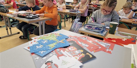Powiększ grafikę: Dzieci piszą życzenia na kartkach pocztowych.