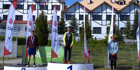 Powiększ grafikę: Zawodnicy z medalami na szyi stoją na podium.