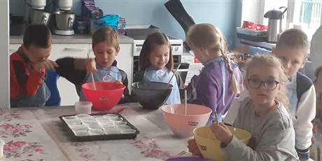 Powiększ grafikę: Dzieci z klasy 1c ugniatają łyżką ciasto na babeczki dyniowe.