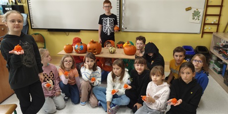 Powiększ grafikę: Uczniowie klasy 3c klęczą przy tablicy prezentując swoje różnorodne dynie.