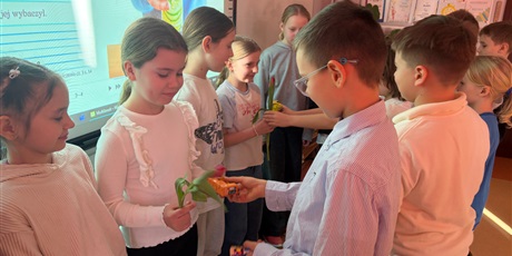 Powiększ grafikę: Chłopcy wręczają dziewczynkom tulipany.