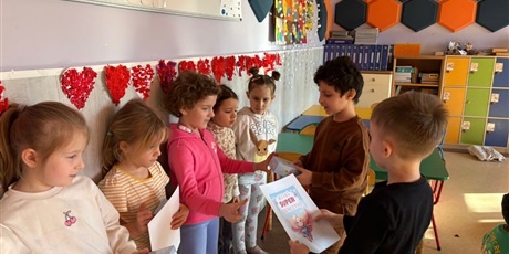 Powiększ grafikę: Chłopcy z zerówki wręczają dziewczynkom dyplomy i upominki.