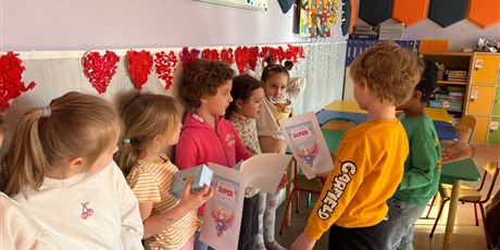 Powiększ grafikę: Chłopcy z zerówki wręczają dziewczynkom dyplomy i upominki.