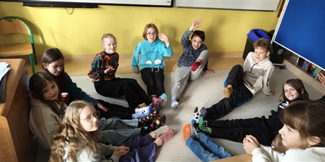 Powiększ grafikę: Uczniowie z klasy 3c na podłodze prezentują w kole swoje kolorowe skarpetki.