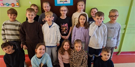 Powiększ grafikę: Dzieci z kl.2b przed drzwiami z zawieszonym plakatem.