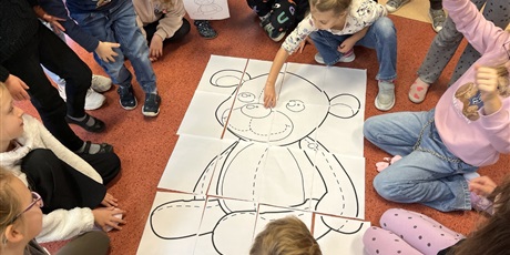 Powiększ grafikę: Dzieci z kl.1b składają misia xxl z puzzli.