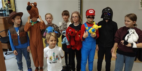 Powiększ grafikę: Dzieci z 3c przebrane za postaci z bajek stoją przy tablicy, trzymają maskotki z bajek.