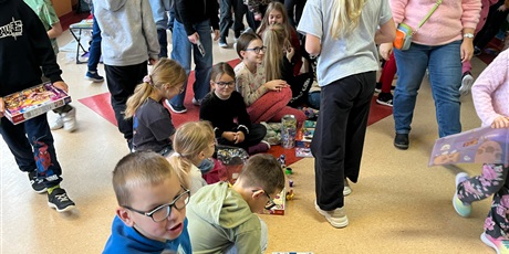 Powiększ grafikę: Uczniowie na holu wymieniają się przyniesionymi przedmiotami.