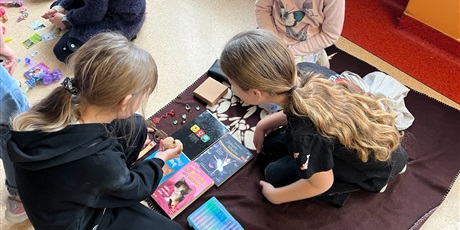 Powiększ grafikę: Uczniowie na holu wymieniają się przyniesionymi przedmiotami.