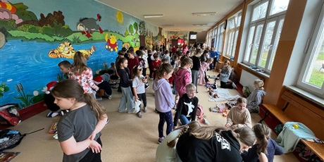 Powiększ grafikę: Uczniowie na holu wymieniają się przyniesionymi przedmiotami.