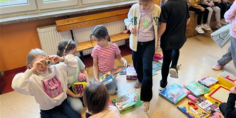 Powiększ grafikę: Uczniowie na holu wymieniają się przyniesionymi przedmiotami.