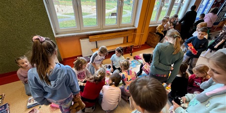 Powiększ grafikę: Uczniowie na holu wymieniają się przyniesionymi przedmiotami.