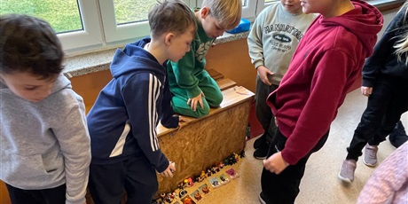 Powiększ grafikę: Uczniowie na holu wymieniają się przyniesionymi przedmiotami.