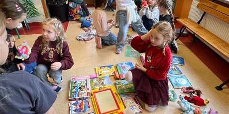 Powiększ grafikę: Uczniowie na holu wymieniają się przyniesionymi przedmiotami.
