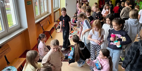 Powiększ grafikę: Uczniowie na holu wymieniają się przyniesionymi przedmiotami.