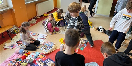 Powiększ grafikę: Uczniowie na holu wymieniają się przyniesionymi przedmiotami.