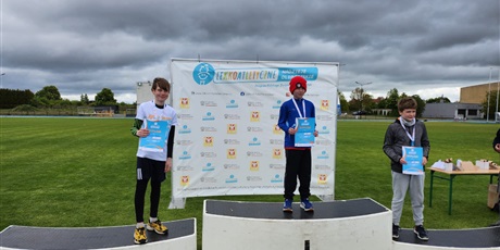 Powiększ grafikę: zawodnicy stoja na podium z medalami na szyi i dyplomami w ręku
