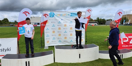 Powiększ grafikę: zawodnicy stoja na podium z medalami na szyi i dyplomami w ręku