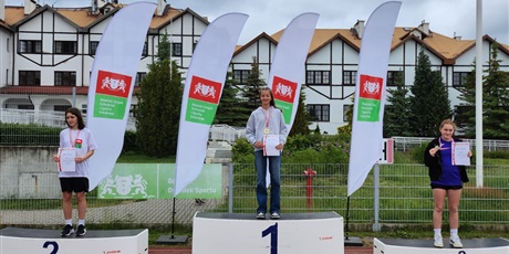 Powiększ grafikę: zawodnicy stoja na podium z medalami na szyi i dyplomami w ręku