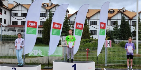 Powiększ grafikę: zawodnicy stoja na podium z medalami na szyi i dyplomami w ręku