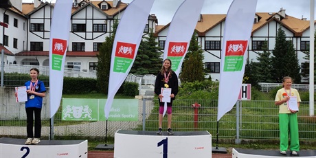 Powiększ grafikę: zawodnicy stoja na podium z medalami na szyi i dyplomami w ręku