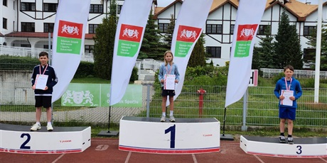 Powiększ grafikę: zawodnicy stoja na podium z medalami na szyi i dyplomami w ręku