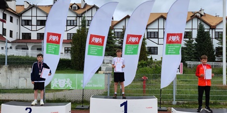 Powiększ grafikę: zawodnicy stoja na podium z medalami na szyi i dyplomami w ręku