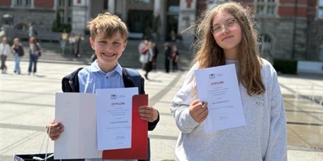 Powiększ grafikę: Uczniowie trzymają dyplomy, stojąc na tle gmachu głównego Politechniki Gdańskiej.