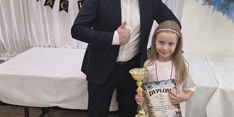Powiększ grafikę: Dziewczynka otrzymuje od jurora puchar i dyplom za zajęcie drugiego miejsca w turnieju szachowym.