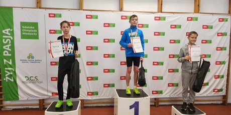 Powiększ grafikę: chłopcy stoją na podium  z medalami na szyi, dyplomem oraz nagrodą rzeczową