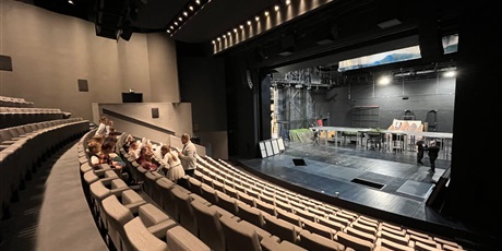 Powiększ grafikę: Dzieci zajęły miejsca na widowni, pan opowiada o teatrze.