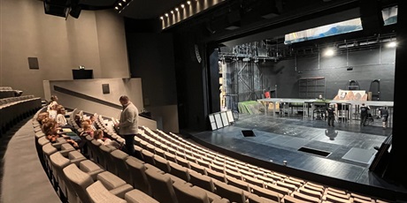 Powiększ grafikę: Dzieci zajęły miejsca na widowni, pan opowiada o teatrze.