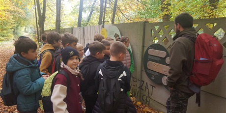 Powiększ grafikę: prowadzący pokazuje ślady pobytu zwierząt w lesie