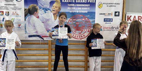 Powiększ grafikę: Dziewczynki stoją na stopniach podium z zawieszonymi medalami i otrzymanymi dyplomami.