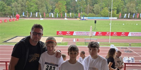 Powiększ grafikę: zawodnicy z trenerem, w tle stadion