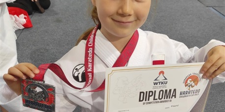 Powiększ grafikę: Dziewczynka prezentuje zdobyty medal i dyplom.