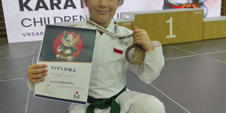 Powiększ grafikę: Dziewczynka prezentuje dyplom i zdobyty medal.