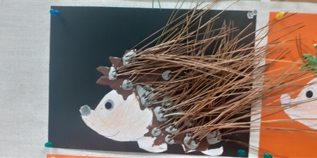 Powiększ grafikę: Praca plastyczna przedstawiająca jeża na czarnym tle  z długimi igłami sosny.